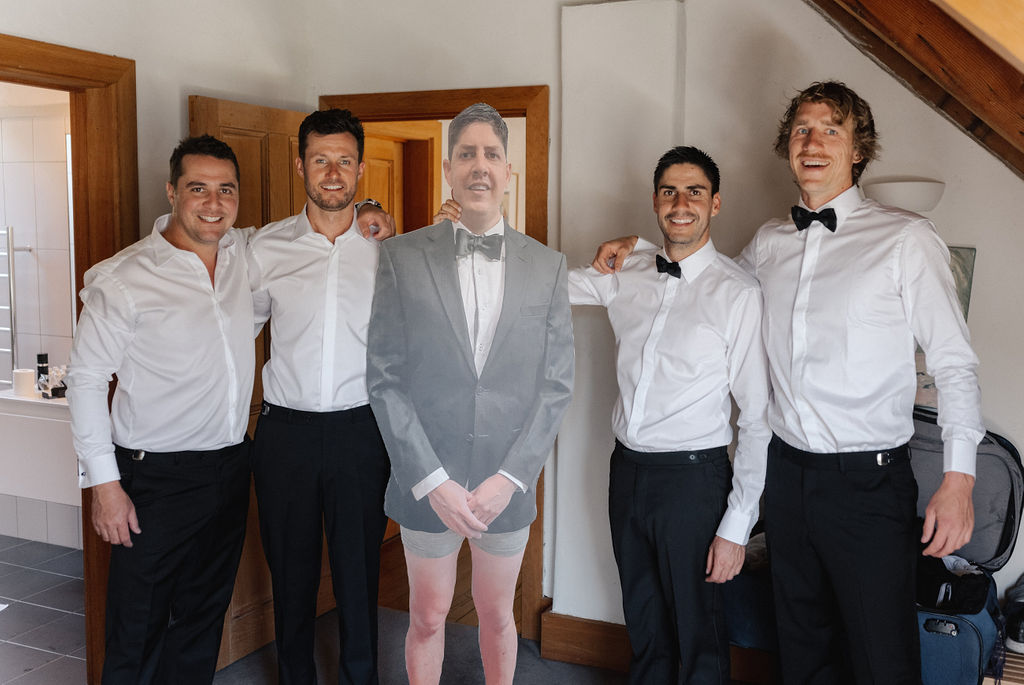 Groomsmen pose with a cardboard cut out of missing groomsman at Queenstown wedding in New Zealand