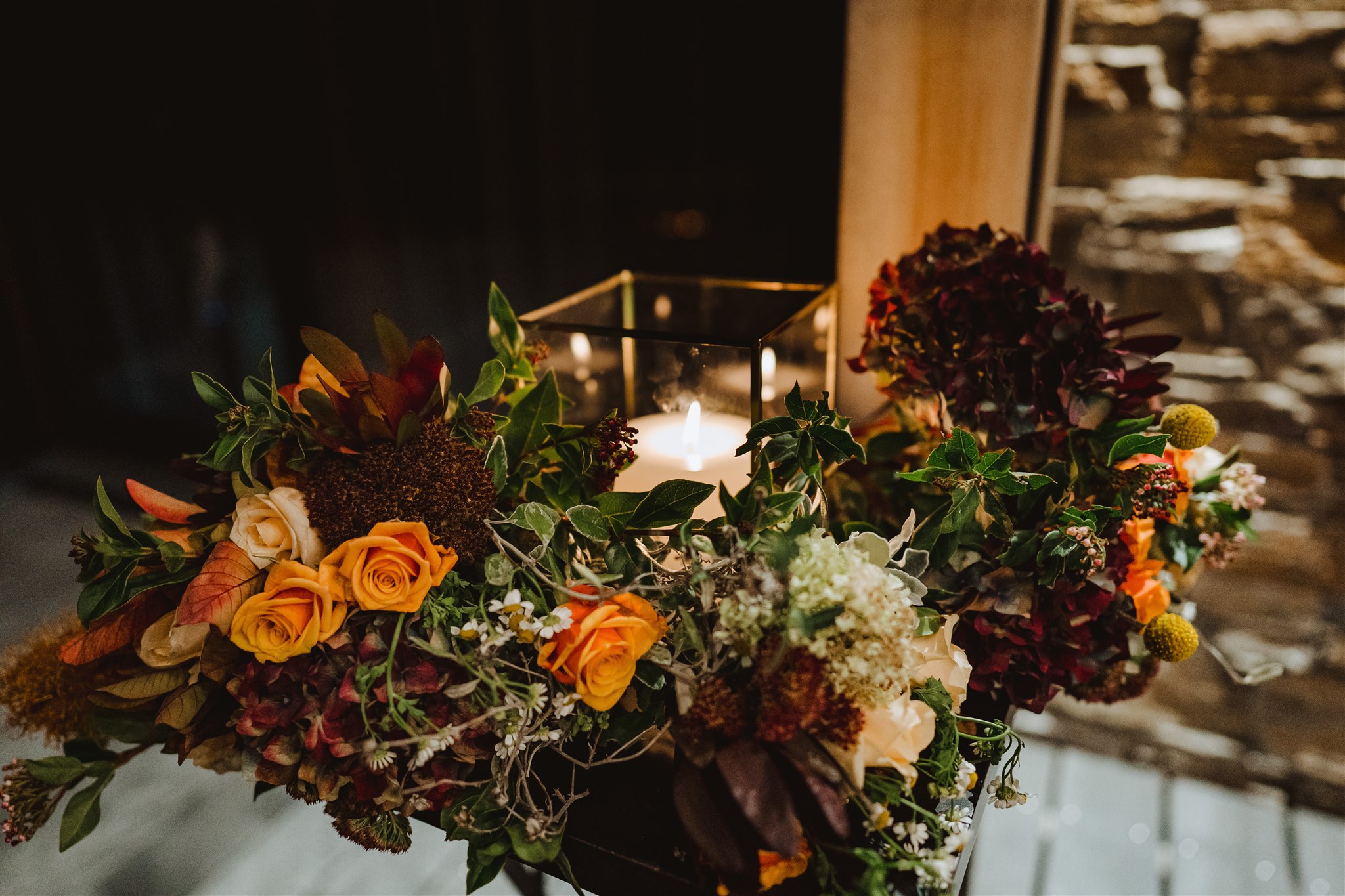 candle burning in a vase surrounding by flowers