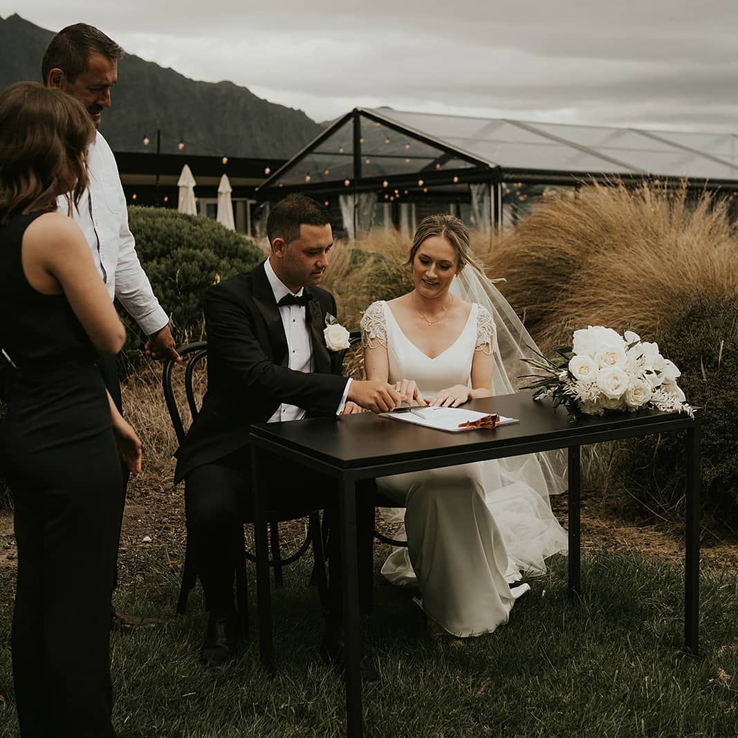 bride and groom signing marriage documents with witnesses at Queenstown wedding in New Zealand