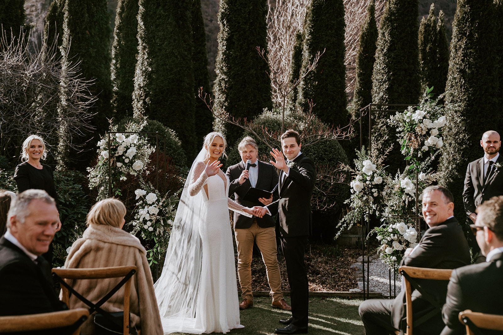 bride and groom wave to the camera during wedding ceremony at Winehouse in Queenstown, New Zealand