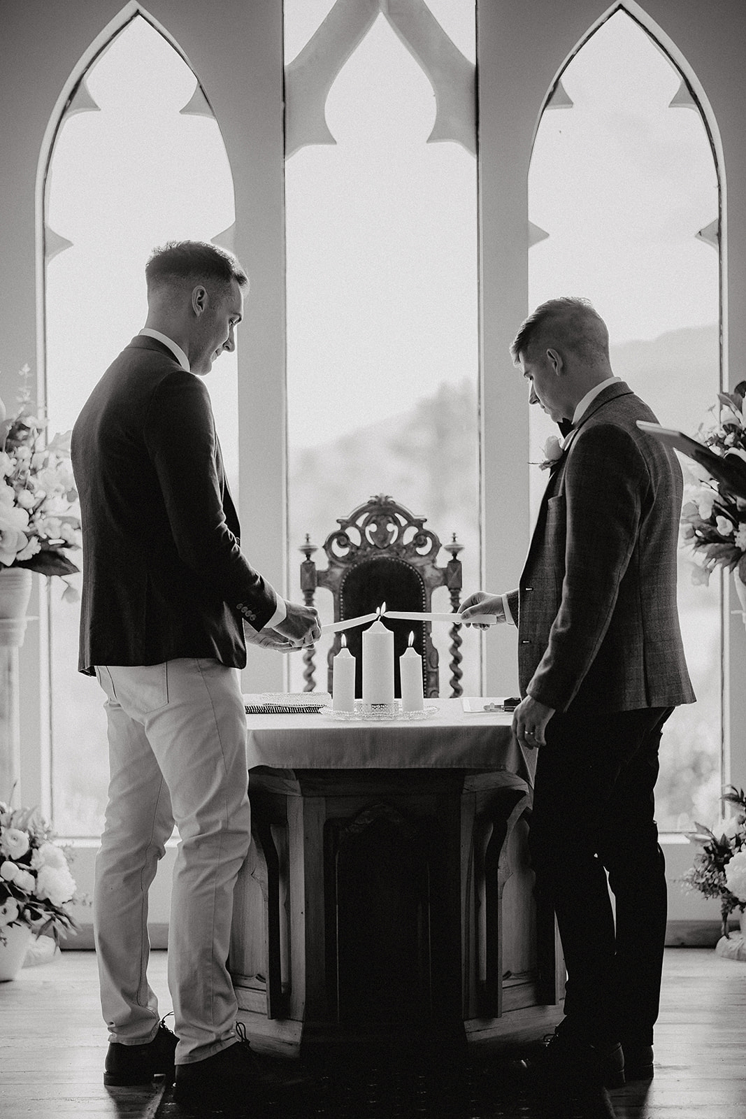 Gay wedding with two grooms lighting a unity candle during wedding ceremony at Stoneridge Estate in Queenstown