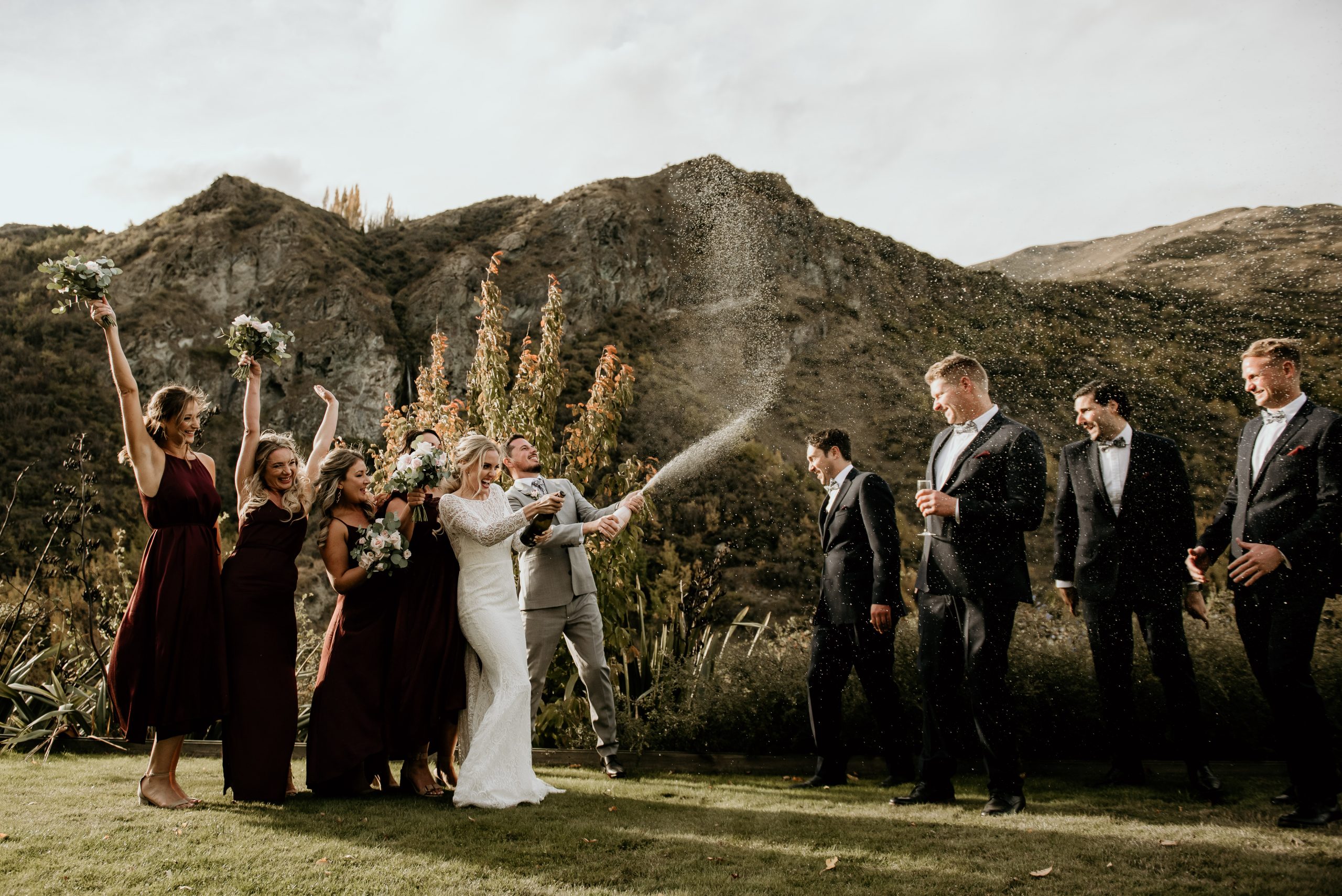 bride and groom spray champagne with their bridal party in Autumn wedding at Winehouse in Queenstown, New Zealand