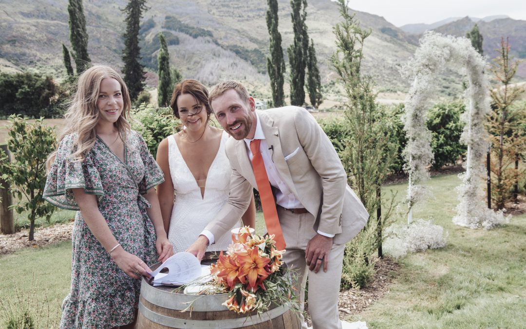 Newlywed couple smile with celebrant after signing marriage paperwork at Queenstown wedding